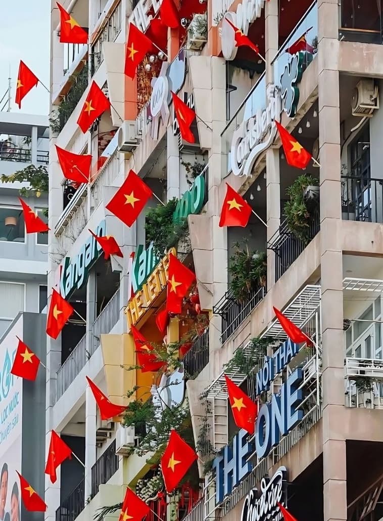 ベトナムの祝日にビルのバルコニーから大量の国旗が掲げられている様子