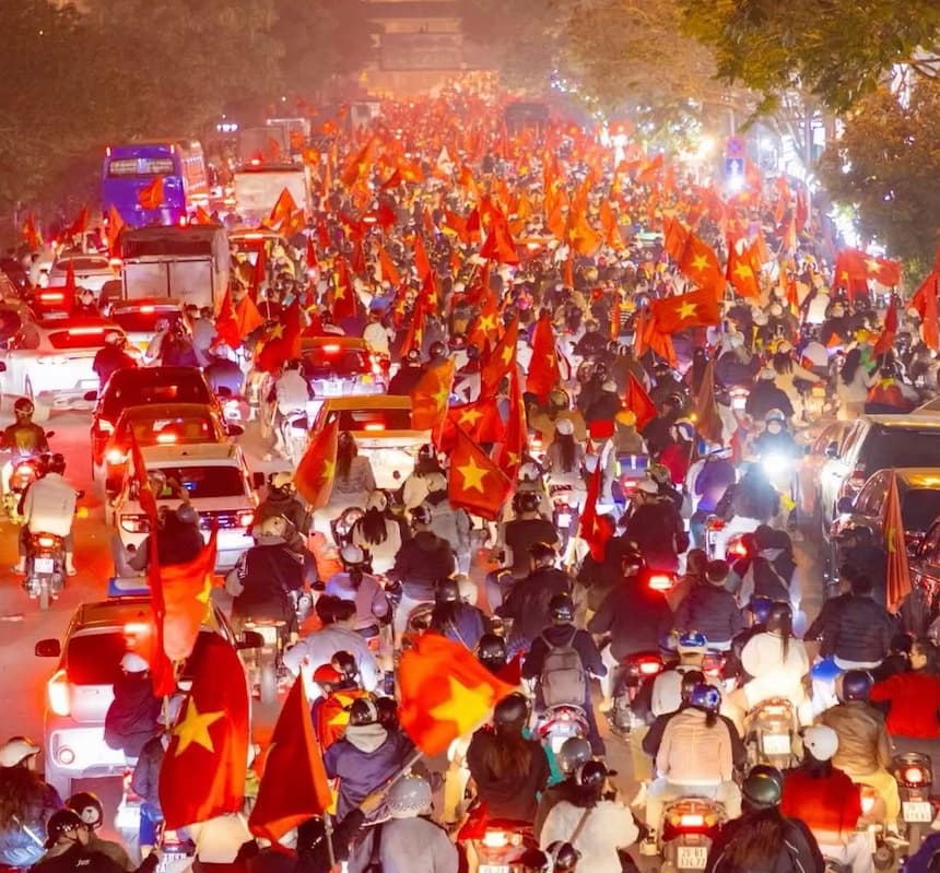 サッカーの勝利後、国旗を掲げてバイクで街を走るベトナムの人々