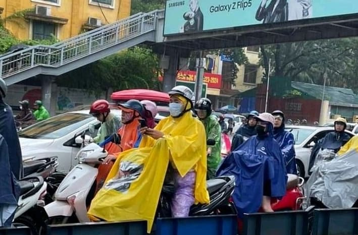 ベトナムの雨の日にカラフルなレインコートを着てバイクで移動する人々