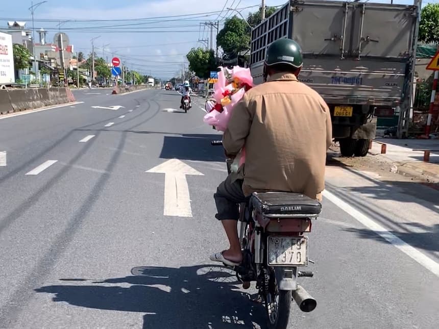 ベトナム女性の日に花束を持ってバイクで走る男性たち(ハノイの街)