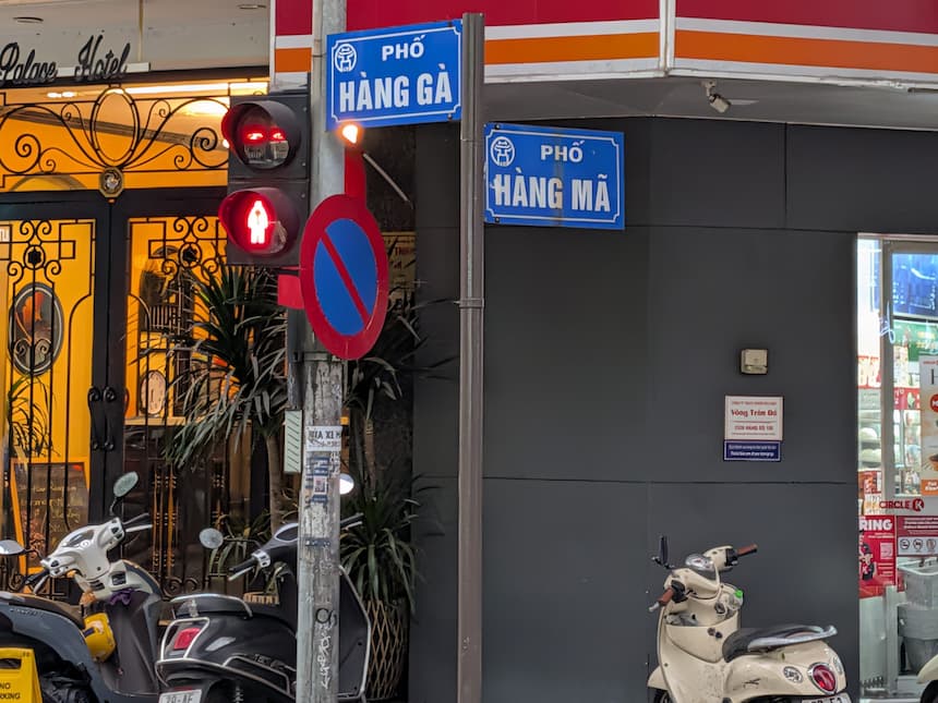 ハノイ旧市街の青い通り名標識「Phố Hàng Gà」と「Phố Hàng Mã」が交差点に並ぶ