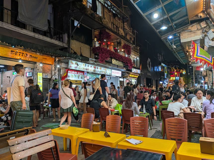 ハノイの有名なターヒエン通り(Tạ Hiện)の夜の賑わい。歩道に並べられたプラスチックの椅子とテーブルで、多くの観光客が食事やお酒を楽しんでいる活気あふれる光景。