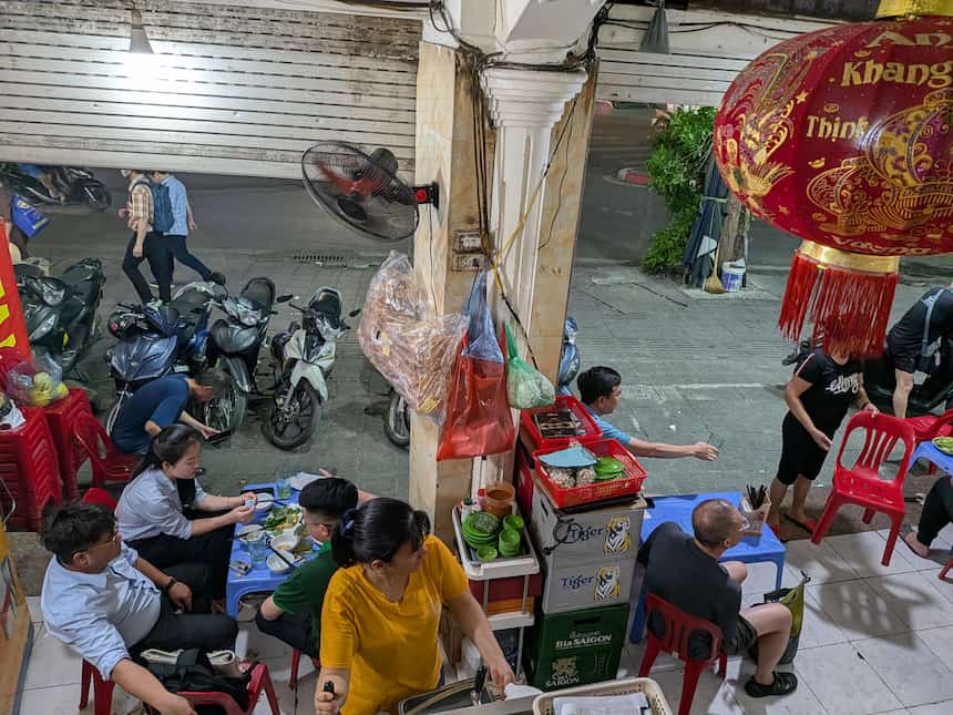 歩道に並ぶビアホイ屋のテーブルを上から見た風景（赤青プラ椅子・地元客）