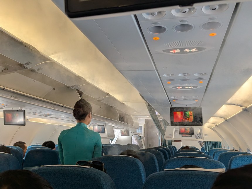 ベトナム航空の客室乗務員が緑のアオザイ制服を着て機内の通路に立つ後ろ姿。航空会社の制服アオザイは、旅行者がよく目にするアオザイのひとつ。