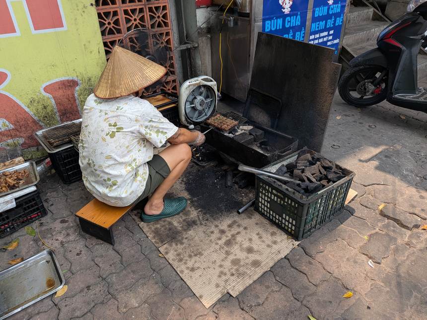 路上の炭火でブンチャー用の豚肉を焼く様子(ノンラー姿の店主、後ろ姿)