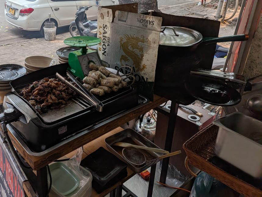 路上の屋台で炭火焼きにされるブンチャーの豚肉と揚げ春巻き（ネム）
