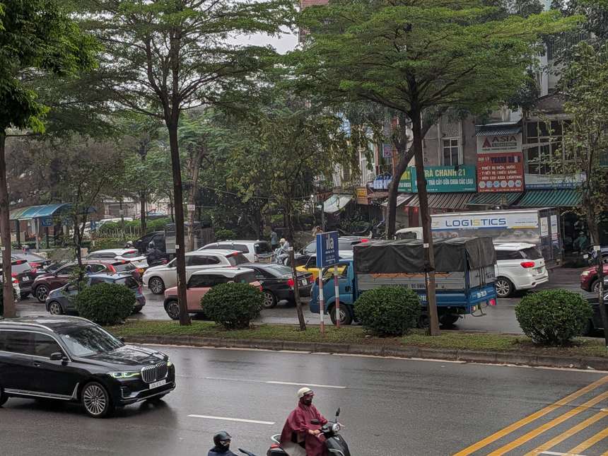 雨のベトナムの交差点を、レインコートやポンチョ姿でバイクが行き交う雨季の街並み