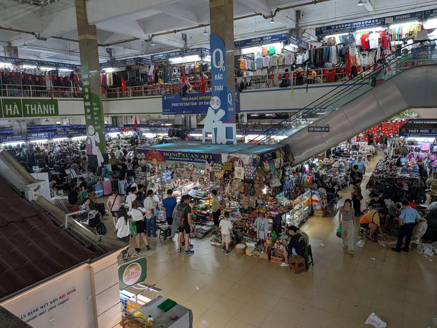 ベトナムの大型屋内市場。多層の売り場に土産物店や衣料品店が並び、多くの買い物客で賑わう。