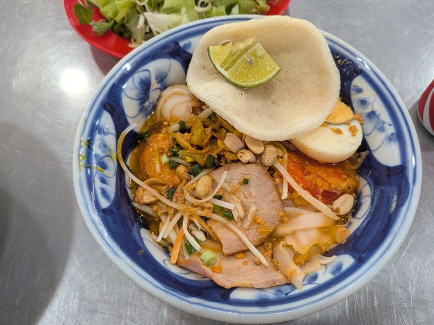 ミークアンの丼。平打ち麺にチャーシュー・海老・ゆで卵・ピーナッツ・揚げ煎餅をのせたダナンの名物麺