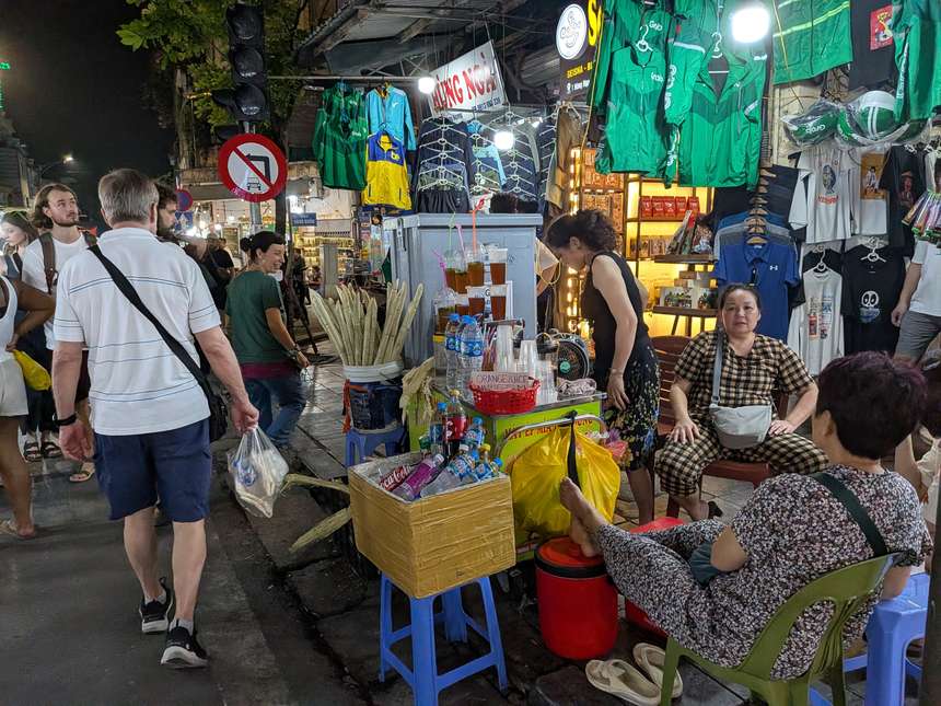 ハノイ旧市街の夜市。サトウキビジュースの屋台や露店が立ち並び、地元の人や観光客でにぎわう路地。