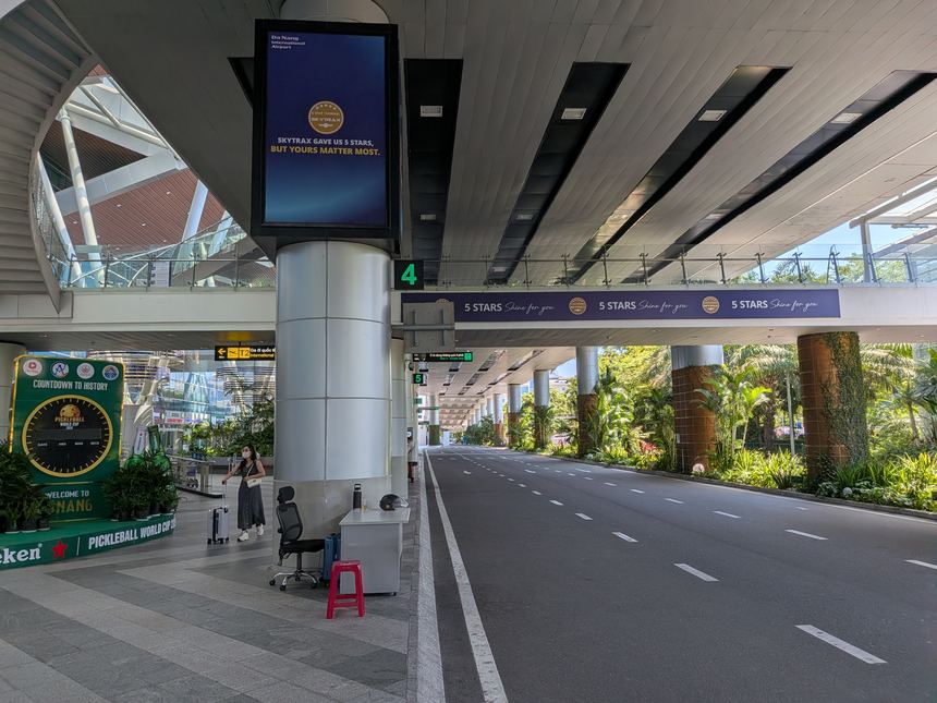 ベトナムの空港のロビー前ピックアップエリア。SKYTRAX5つ星認定のバナーが掲げられ、熱帯植物が並ぶ車道。