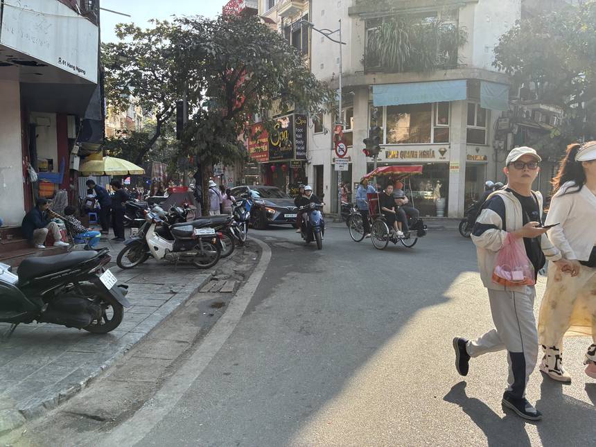 ベトナムの旧市街の交差点を行き交うバイクとシクロ（人力三輪タクシー）。