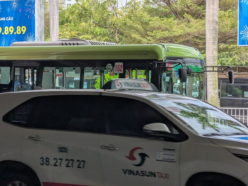 大手タクシー「Vinasun(ビナサン)」の車両(電話番号 38.27.27.27)と背後の152番バス