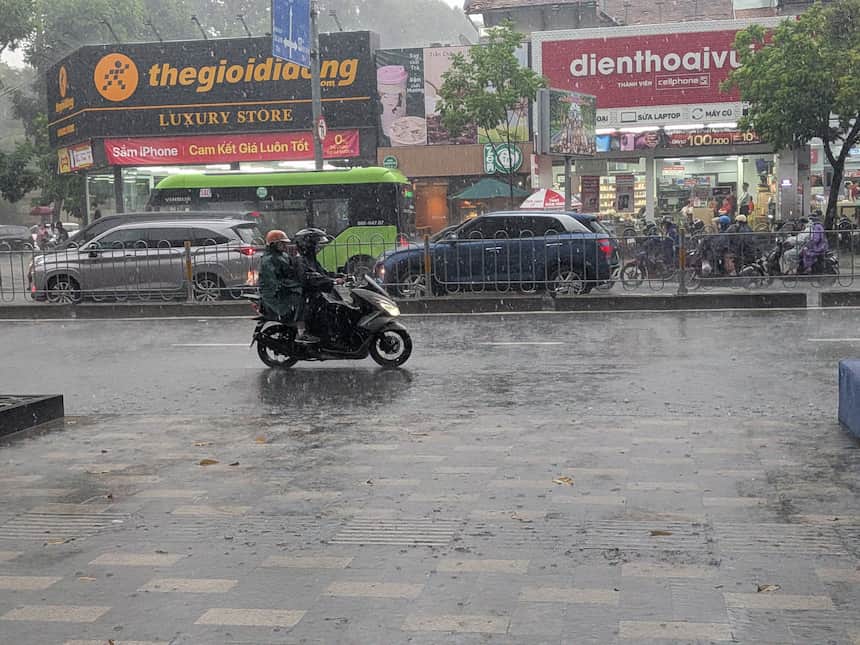 雨季のホーチミン、ポンチョ姿で激しい雨の中を走るバイク
