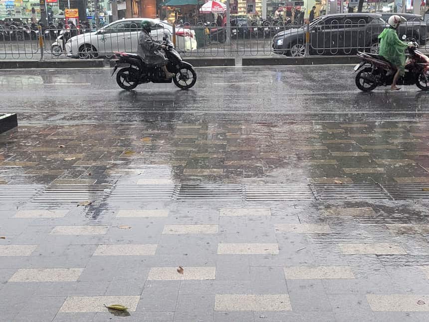 雨季の午後、激しいスコールで濡れたホーチミンの歩道とバイク