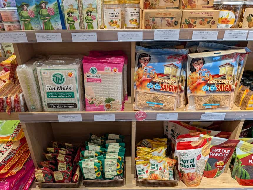 フオンベトの棚に値札付きで並ぶパッケージされたベトナムの食品土産(ライスペーパー、おこし、瓜の種など)