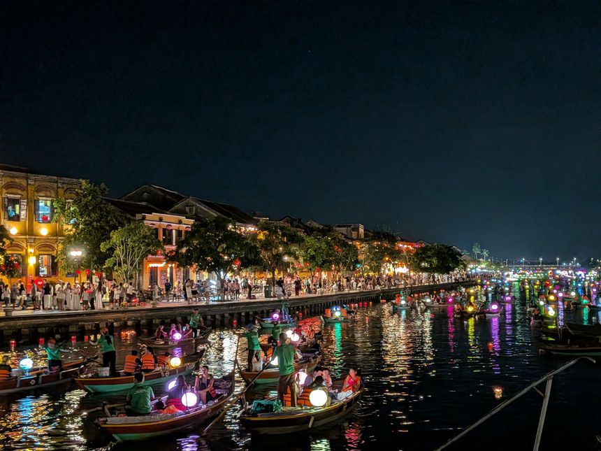 夜のホイアン、トゥボン川のランタン祭り。灯籠を載せた小舟と旧市街の灯りが川面に映る