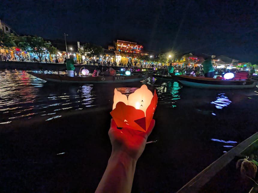 ホイアンで火を灯した紙の灯籠(水灯籠)を水面に置く手元のアップ
