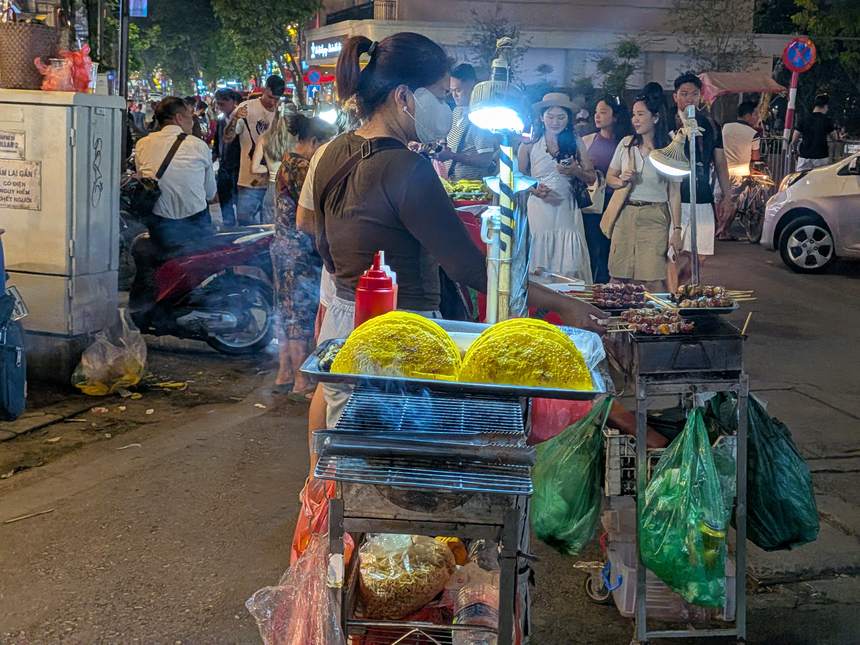 ベトナムのナイトマーケットの屋台。炭火グリルで焼く串料理や丸い形の食べ物が並び、食べ歩きの定番が揃う夜の繁華街。