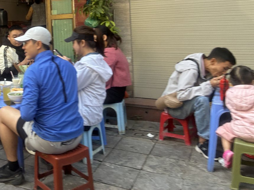 ベトナムの路地で朝食のフォーを食べる人々