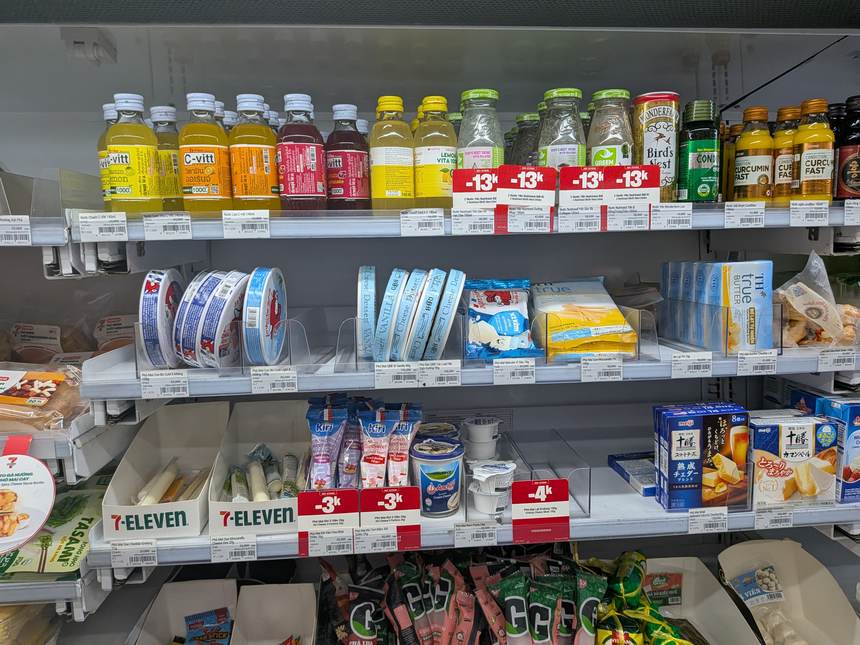 ベトナムのセブンイレブン店内。ドリンクや食品が割引価格タグとともに棚に並ぶ。水やコンビニ弁当など日用品の相場がわかる。