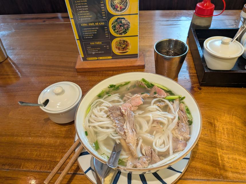 ベトナムの食堂で出される牛肉フォー(Phở bò)の丼。澄んだスープにたっぷりの米麺と薄切り牛肉、青ねぎが盛られている。1杯50,000〜70,000ドン前後が相場。