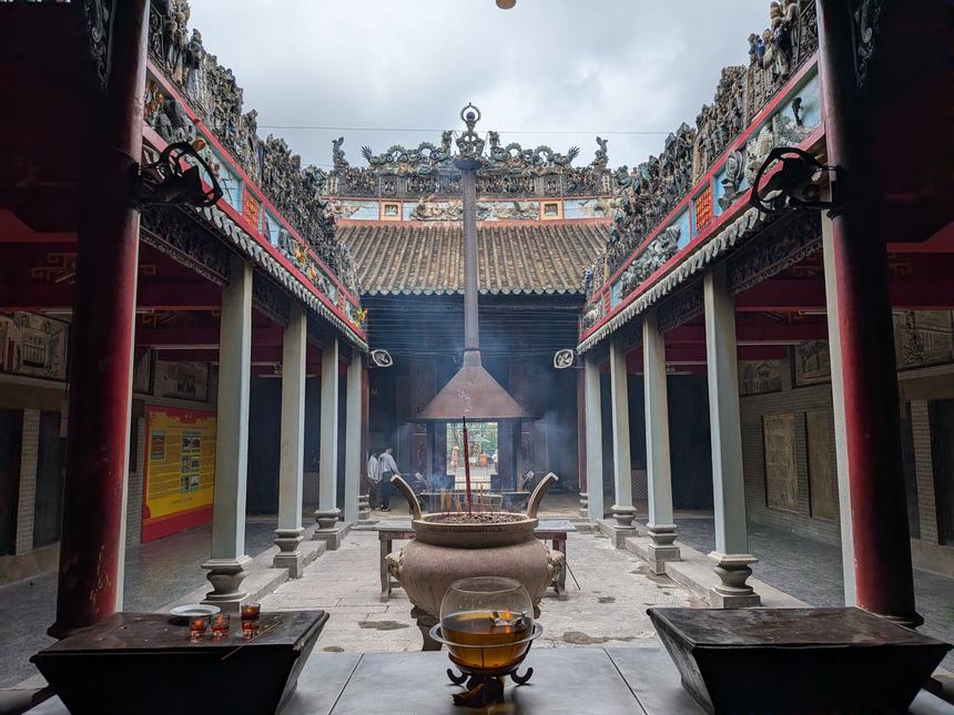 ベトナムの中国系寺院(華人廟)の中庭。龍や神像で飾られた極彩色の屋根の下、大型の香炉から線香の煙が立ちのぼる。