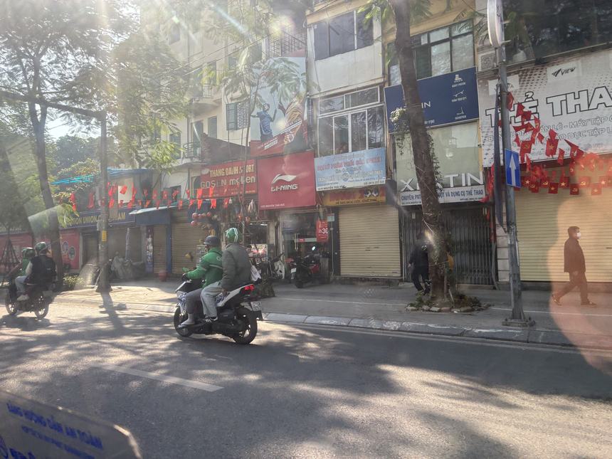 テト(旧正月)の赤い飾りが付いた通りで、シャッターを閉めた商店が並ぶ朝の風景。家族経営の店は休みに入る。