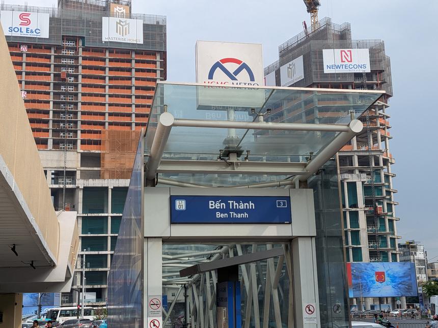 ホーチミン市メトロ・ベンタイン駅の入口と、背後に建ち並ぶ建設中の高層ビル。