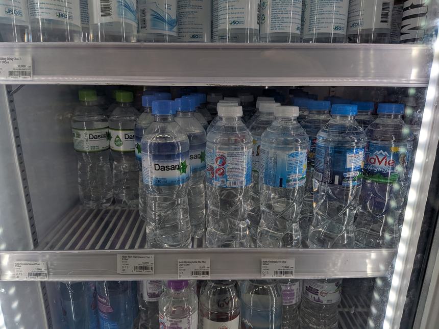 ベトナムのコンビニの冷蔵ショーケースに並ぶミネラルウォーター(Dasani・LaVieなど)。500mlで約30〜50円と安く、旅行者はこれを常に持ち歩くのが基本。