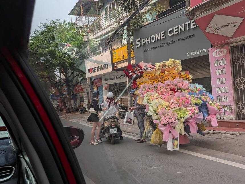 ベトナムの街角の花売り露店。色とりどりの花束が大量に並び、バイクで訪れた客が花を選んでいる。