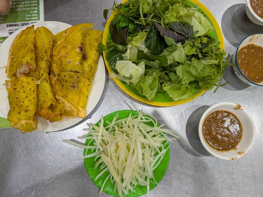 バインセオ バーユンのバインセオの皿。葉物野菜、青パパイヤの千切り、茶色いタレが並ぶ