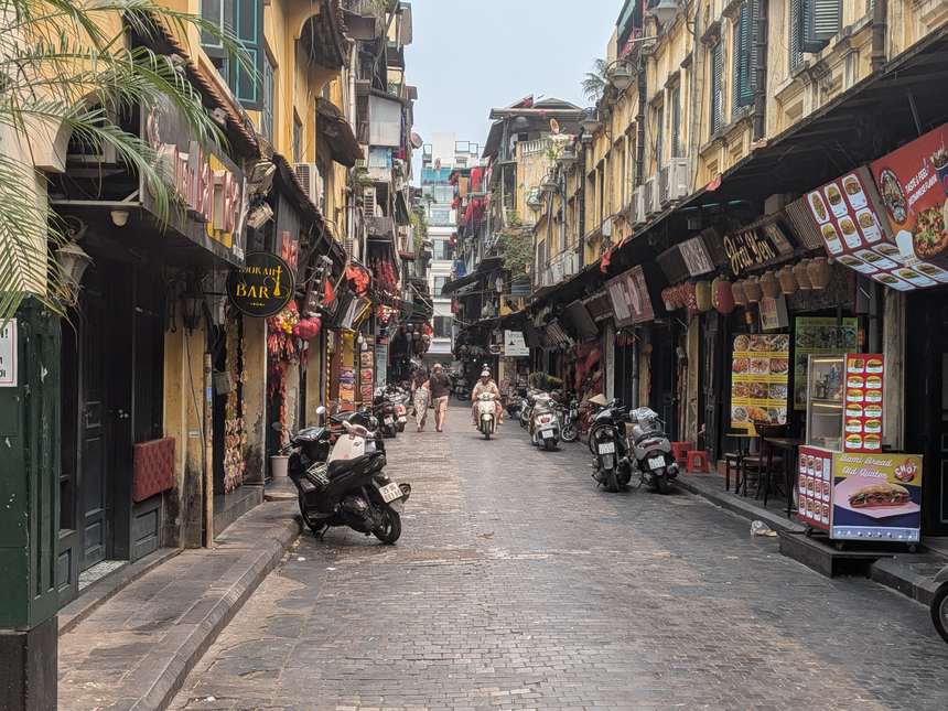 ハノイ旧市街の石畳の路地。商店が軒を連ね、歩行者が行き交う