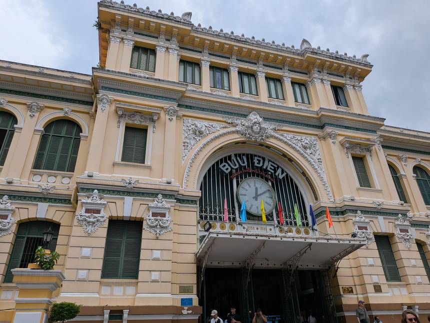 ホーチミン中央郵便局の正面。アーチ上部に「BƯU ĐIỆN THÀNH PHỐ HỒ CHÍ MINH」の文字と時計が掲げられている