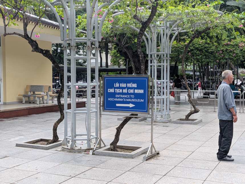 ホーチミン廟の入口を示す青い案内板。「LỐI VÀO VIẾNG…／ENTRANCE TO HOCHIMINH'S MAUSOLEUM」と書かれ、矢印で入口の方向を示している