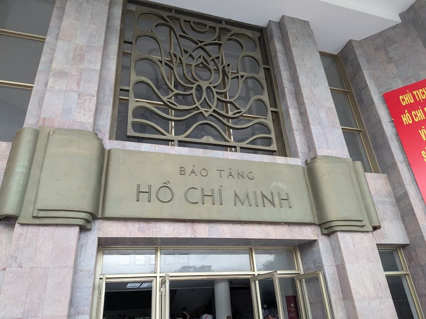 ホーチミン博物館の入口。「BẢO TÀNG HỒ CHÍ MINH」と刻まれた金色の看板と、蓮の花をかたどった装飾格子が掲げられている