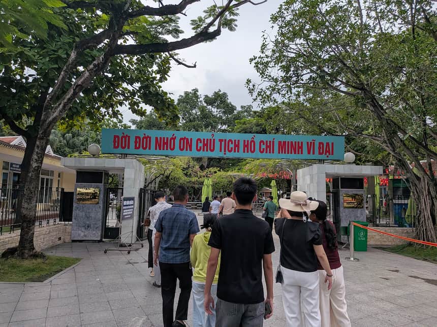 ホーチミン廟の見学者用入口の門。「ĐỜI ĐỜI NHỚ ƠN CHỦ TỊCH HỒ CHÍ MINH VĨ ĐẠI（偉大なるホー・チ・ミン主席への感謝を永遠に）」と書かれた緑の横断幕の下を、見学者が敷地の中へ入っていく