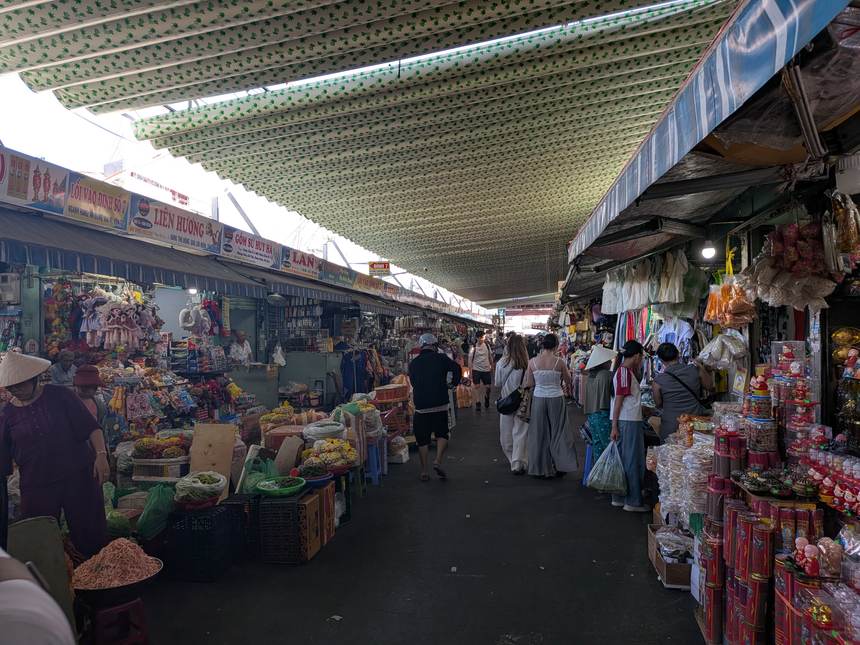 コン市場の屋外の通路。テントの下に乾物や仏具の露店が並び、買い物客が歩いている