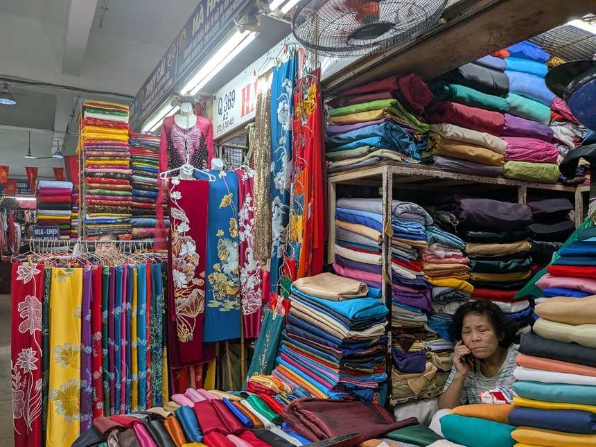 ドンスアン市場の生地売り場。アオザイ用の反物と色とりどりの布が天井まで積まれている