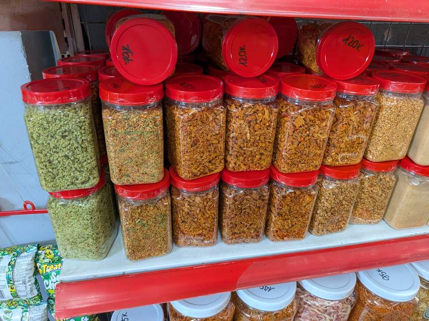 ホーチミンの乾物店でジャーの蓋に直接書かれたバインチャン系スナックの値段(76,000〜120,000ドン)
