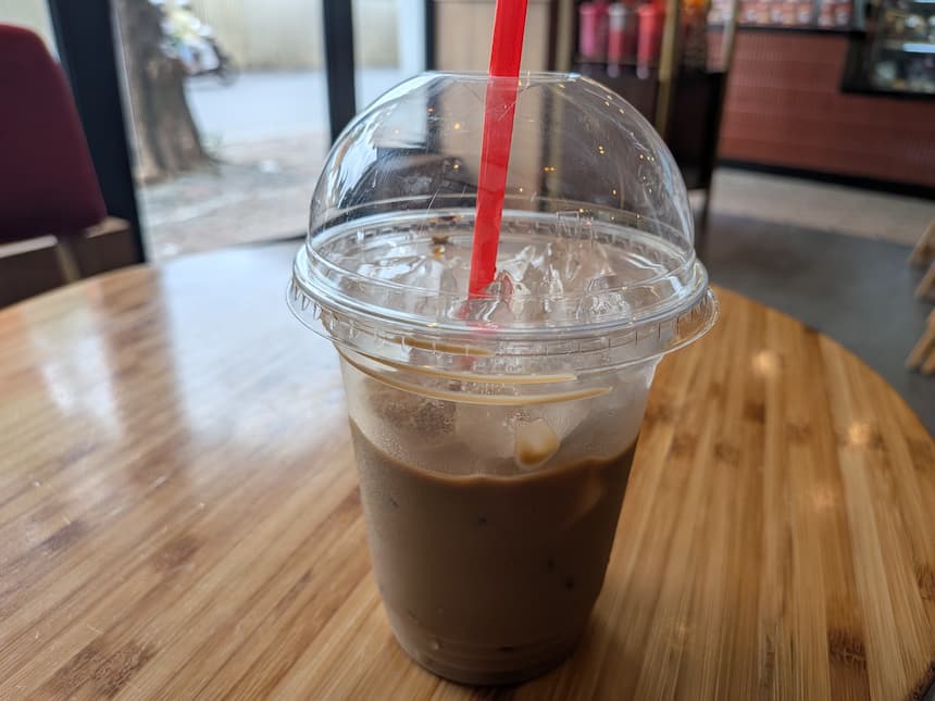 木のテーブルに置かれたハイランズコーヒーのカフェスアダー(練乳入りアイスコーヒー)