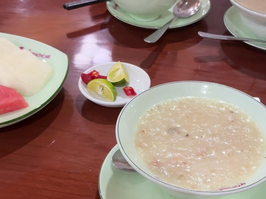 マッサージ店で施術後に出る軽食一式。粥の椀と、ライムと輪切り唐辛子の小皿、スイカの皿が並ぶ