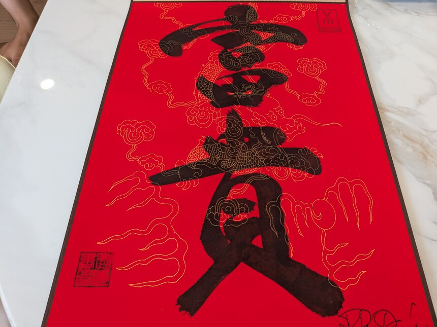 文廟で書いてもらった書道。赤地に金の雲龍紋の色紙に「富貴」の字と落款