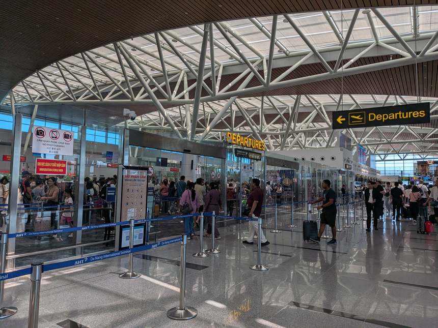 ダナン国際空港の出発フロア。Departuresの案内の先にある出国審査へ向かって、乗客が列をつくっている。