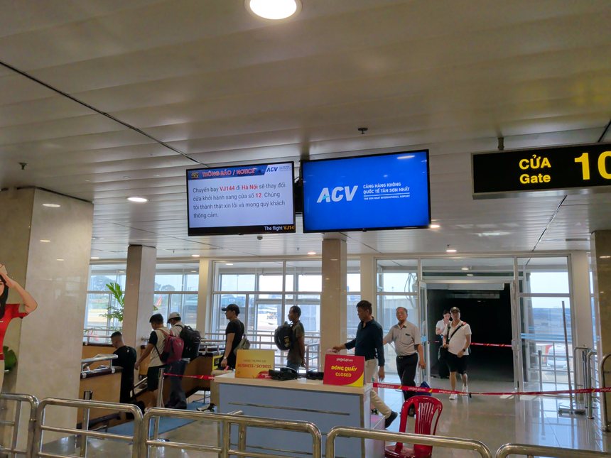 タンソンニャット国際空港の搭乗ゲート10番付近。ハノイ行きVJ144便の搭乗ゲートが12番へ変更になったという案内が表示され、ベトジェットのカウンターには閉鎖中の札が出ている。