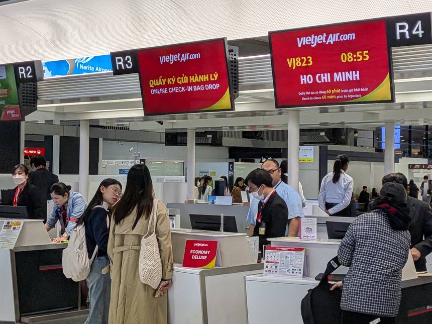 成田空港のベトジェットのチェックインカウンター。ONLINE CHECK-IN BAG DROPの表示と、ホーチミン行きVJ823便のチェックインは出発の60分前に締め切るという案内が出ている。