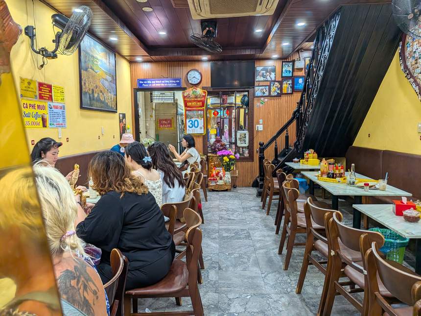 バインミーフーンの店の奥にあるテーブル席。木の椅子とテーブルが並び、壁に写真が飾られている