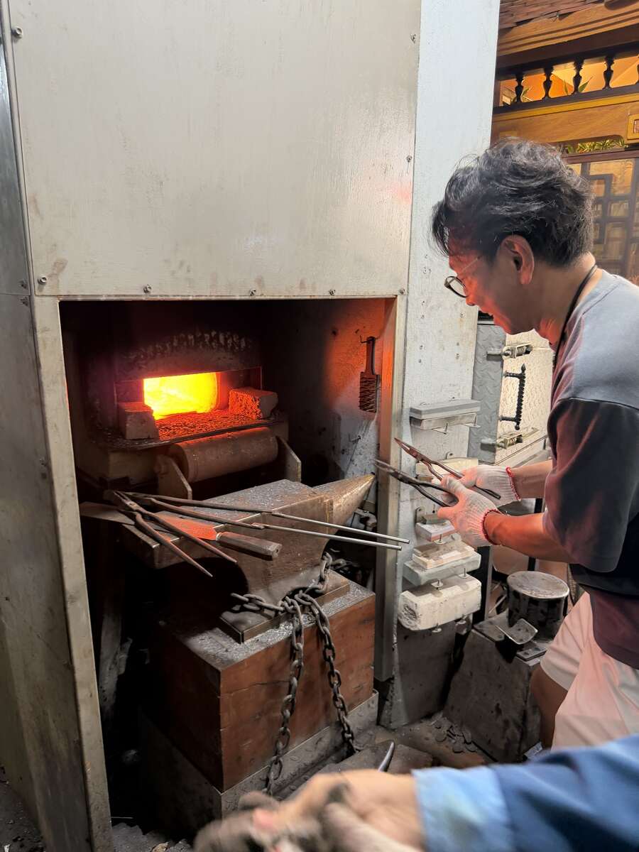 炉の前で鋼を扱う、レ・ラム工房での鍛冶体験の様子