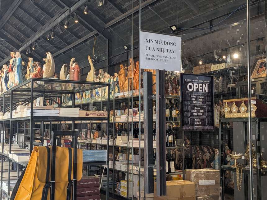 ハノイ大教会の敷地にある書店。聖像が棚に並び、入口に営業時間を書いたOPENの看板