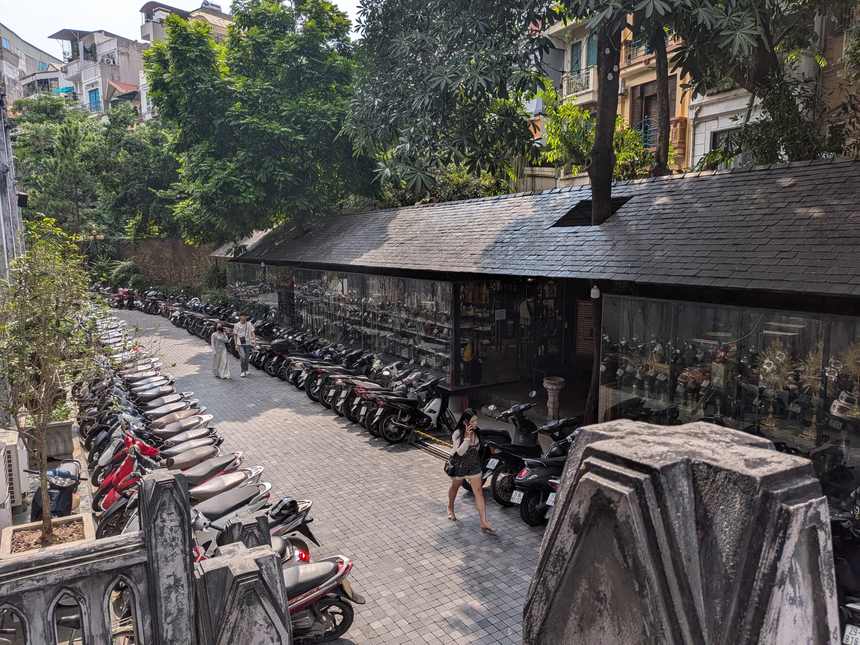 ハノイ大教会の右側、出口側の通路。バイクが並び、ガラス張りの細長い書店の建物が続く